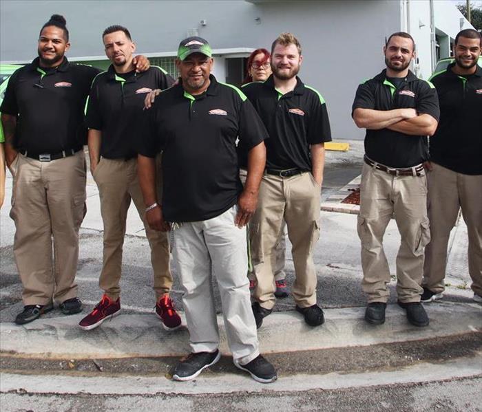 Crew photo, employees are in a row wearing black polos. 