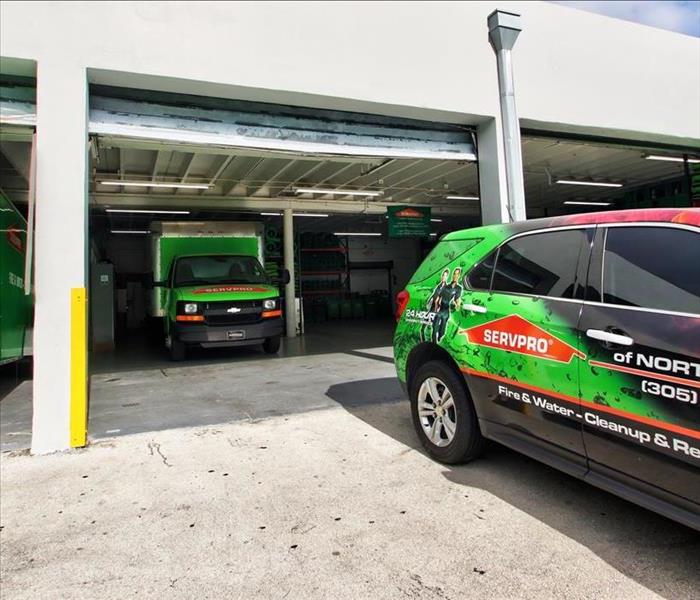 Garage with a green SERVPRO truck inside, and one outside.