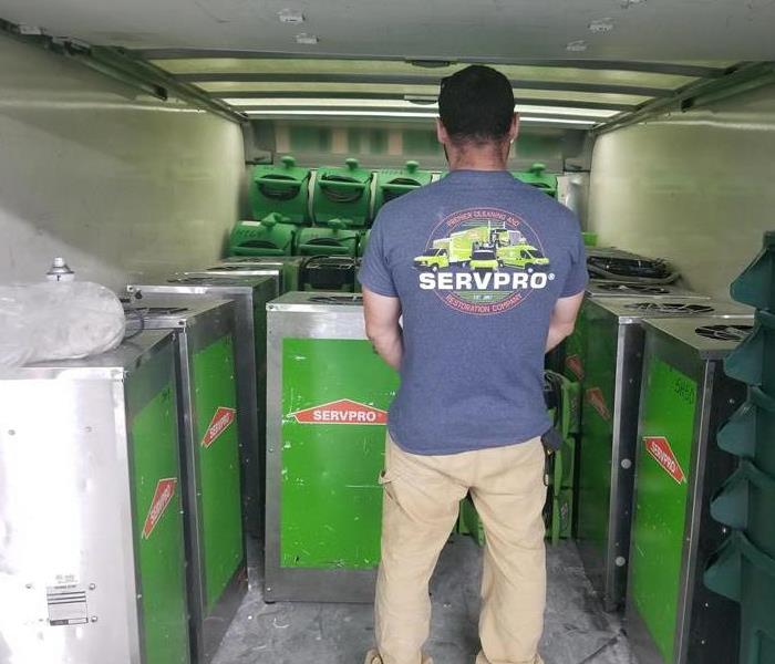 Employee standing in the bed of a SERVPRO green truck checking stock. 