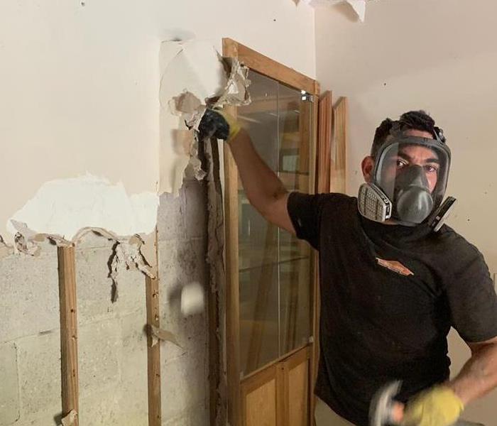 Employee in a protective mask breaking down drywall. 